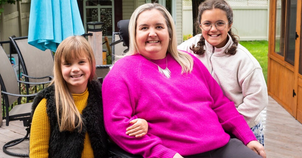 Anne-Marie Marcil with her two daughters, all smiling together at home.