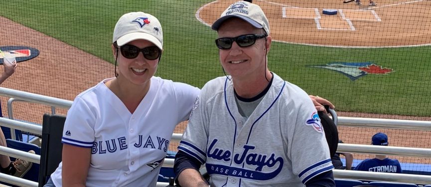 Mike Cels and a companion at a Blue Jays game, both wearing Blue Jays gear.