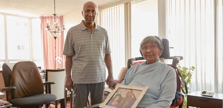 Susheela Balasingham sitting with a caregiver in a living room.